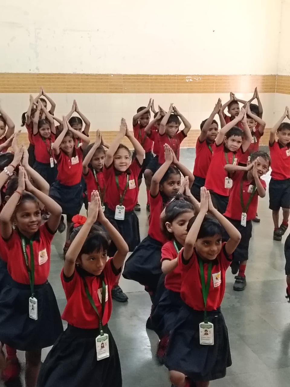 Students practising yoga tree pose in the school hall